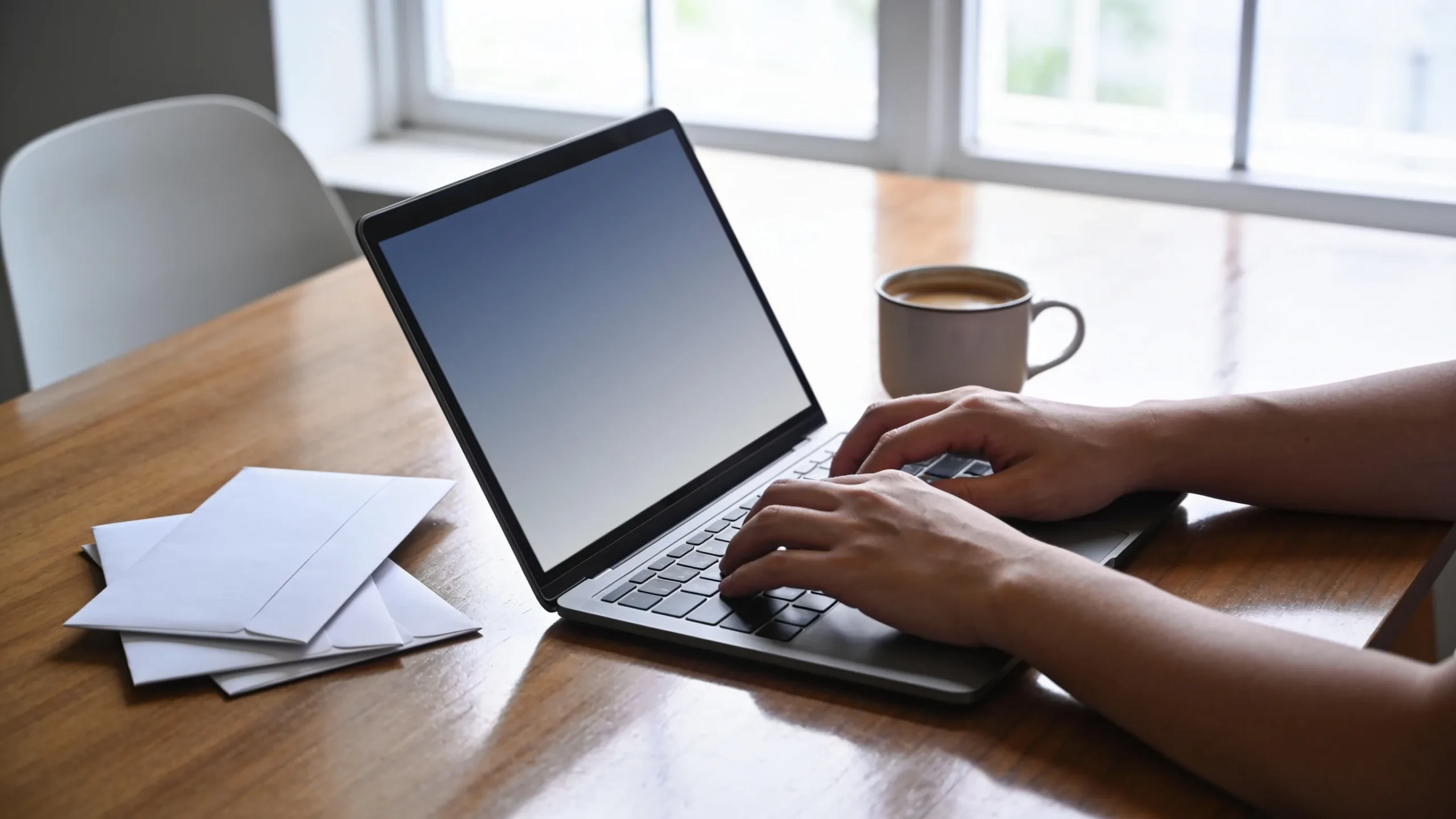 Persona escribiendo una carta de reclamacion con IA en su portatil junto a varios sobres